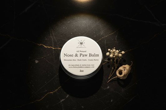 Nose and paw balm tin on dark marble with gold accents and warm dramatic lighting